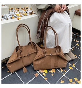 Detail of brown matte leather tote bags with metal buckles on autumn outdoor steps
