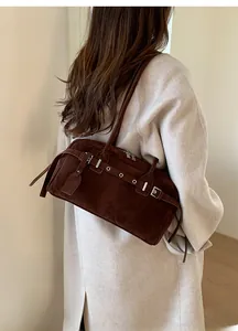 Model wearing a dark brown suede underarm bag with retro metal eyelet strap detail