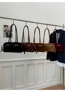 Row of minimalist leather shoulder bags in five colors hanging on a metal rack