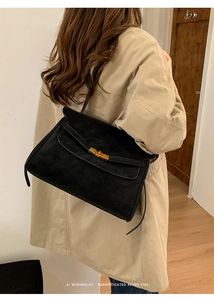 Detail einer Retro-Handtasche aus schwarzem Wildleder mit goldenem Metallverschluss
