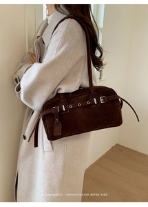 Macro view of dark coffee suede underarm bag with silver buckle and leather tag detail