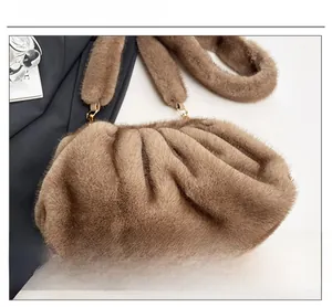 Close-up of brown plush faux fur cloud bag with pleated texture and gold hardware hooks