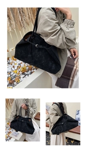 Detail view of large black matte suede tote bag with decorative straps and silver buckles