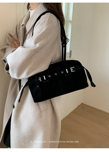 Close-up of black suede retro bowling shoulder bag with silver buckle and eyelet straps