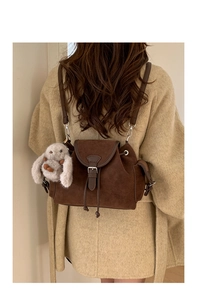 Detail of dark brown vintage suede bucket bag with drawstring and plush rabbit charm