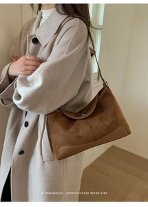 Detailed view of dark brown suede shoulder bag featuring retro metal twist lock closure