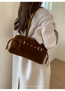 Detail of dark brown suede shoulder bag with silver buckle and metallic eyelets