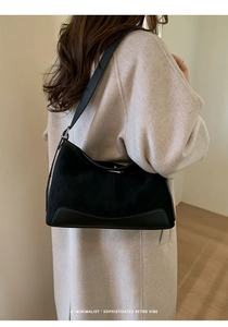 Detail of minimalist black matte suede underarm bag with adjustable leather strap