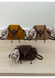 Detailed view of suede texture bucket bags with leather trim and plush bunny charms