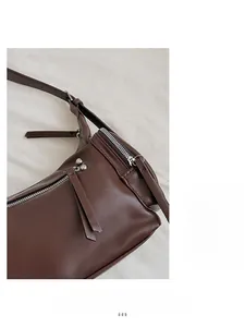 Detail of dark brown leather handbag with smooth texture and silver metal zippers