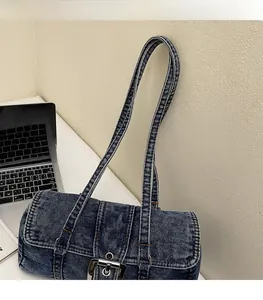 Détail du sac cylindrique en denim délavé bleu foncé avec boucles métalliques argentées