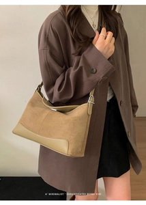 Detail view of khaki suede and matte leather patchwork on a minimalist underarm bag