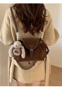 Close-up of brown suede mini backpack with drawstring closure and cute plush rabbit charm