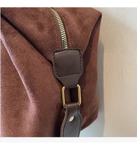 Close-up of premium brown suede tote bag featuring gold hardware and secure zipper closure