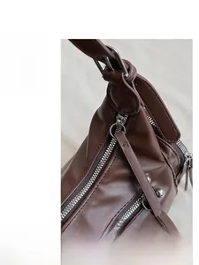 Close-up of smooth silver zippers and strap metal hardware on deep brown leather bag