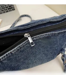 Gros plan sur la fermeture éclair en métal argenté du sac Boston en denim bleu