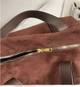Close-up of golden metal zipper and suede texture on a vintage brown tote bag