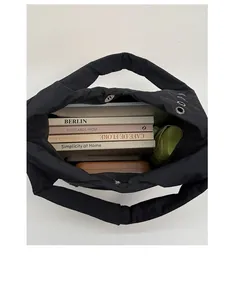 Top view of spacious black quilted tote bag interior holding books, umbrella and tablet