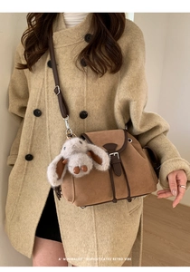 Detail of brown suede crossbody bag with vintage buckle and cute grey rabbit charm