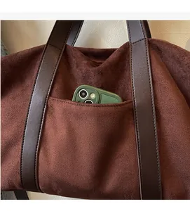 Detail of minimalist dark brown suede tote bag showing functional front pocket for smartphone