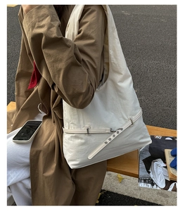 Detail of a minimalist cream-white shoulder bag with silver buckle and belt texture