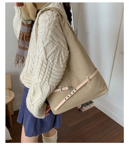 Close-up of khaki nylon tote bag with decorative leather strap and metal buckle detail