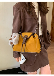Close-up of a mustard yellow suede crossbody bag with retro leather trim and rabbit charm