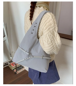 Detail view of the gray shoulder bag showing metal eyelets and decorative buckle straps