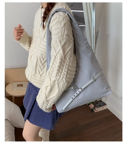 Close-up of light gray large canvas crossbody bag with decorative leather strap buckle
