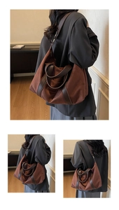 Detail of a large brown suede tote bag with leather handles and reinforced bottom edges