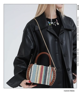 Close-up of a colorful woven straw handbag with rivets and brown leather handles