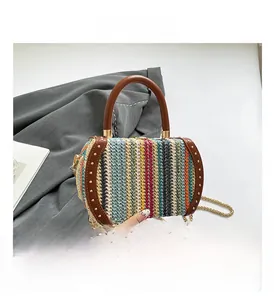 Detail of colorful woven cylinder bag featuring brown leather trim and metal rivets