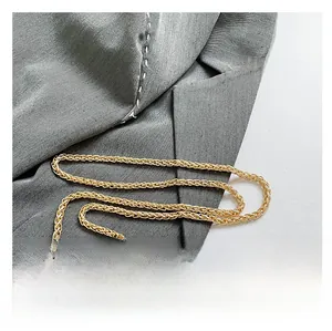 Detailed macro view of high-quality golden woven metal chain strap with leather handle