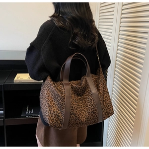 Detail of the leopard print tote bag featuring brown leather handles and canvas texture