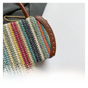 Detailed macro view of colorful woven straw bag with brown leather trim and golden metal studs