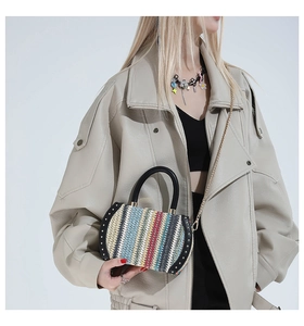 Detail of multi-color woven straw handbag with vertical stripes and gold chain strap