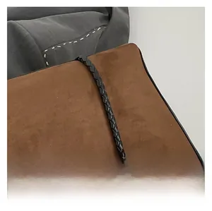 Close-up of brown suede tote bag featuring intricate black braided leather shoulder straps
