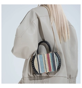Detail of colorful woven handbag with vertical stripes, black handle and gold rivets