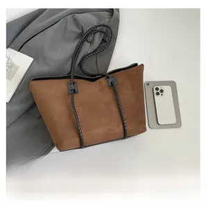 Detail view of large brown suede tote bag with black woven handles and metal feet