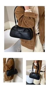 Detail of black pebbled leather bowling bag with vintage stitching and long shoulder straps