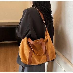 Close-up of a large vintage brown tote bag with leather straps on a model in a warm room