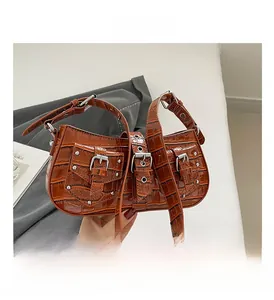 Detail of dark brown crocodile pattern leather shoulder bag with silver metal buckles