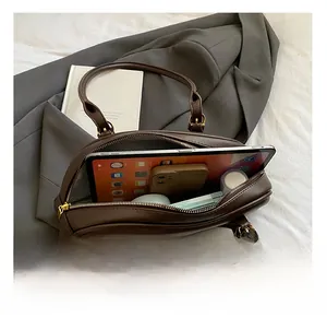Top view of spacious interior of brown pebbled leather bag with tablet and cosmetics