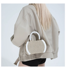 Detail of straw woven crossbody bag with white leather trim and metal rivets