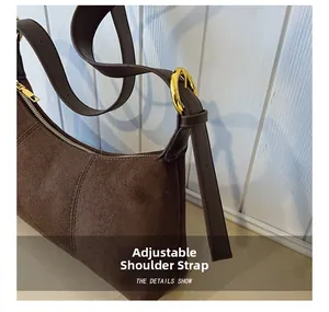 Detail of adjustable strap and golden hardware on dark brown suede hobo shoulder bag