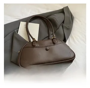 Detail of dark brown lychee leather handbag with golden hardware on grey blazer background