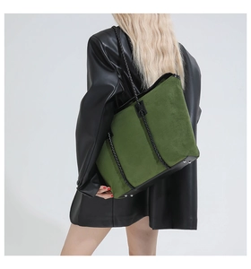 Detail of forest green suede tote bag with woven shoulder strap and black leather accents