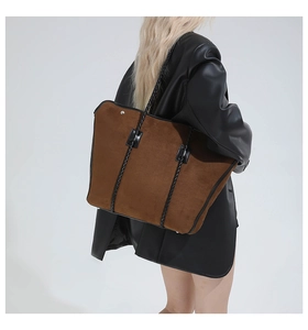 Detail of a large vintage brown suede tote bag with black woven handles on shoulder