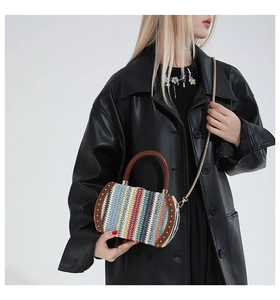 Detail of colorful woven handbag featuring vertical stripes with rivets and gold chain