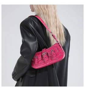 Detail of pink faux crocodile skin texture and silver metal rivets on the punk shoulder bag